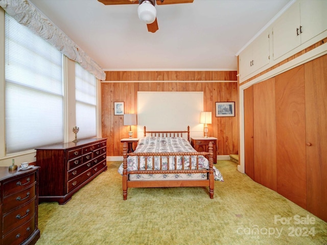 bedroom with wooden walls, light carpet, and ceiling fan