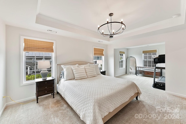 bedroom with a tray ceiling, light colored carpet, and a chandelier