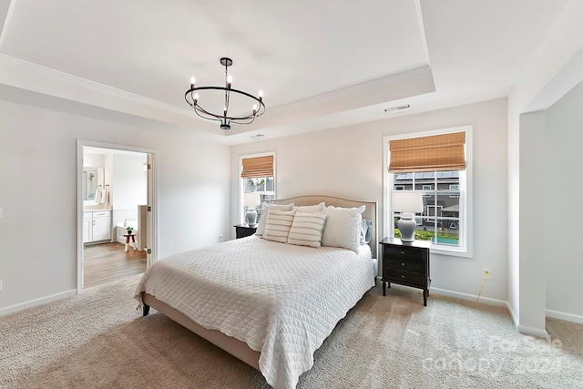 bedroom with carpet floors, a raised ceiling, ensuite bath, and a chandelier