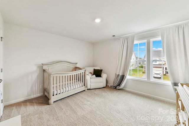 bedroom with light colored carpet and a nursery area