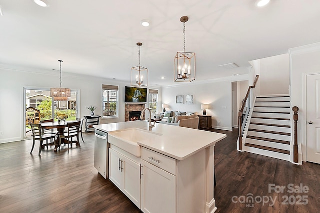 kitchen featuring decorative light fixtures, a sink, open floor plan, light countertops, and a center island with sink