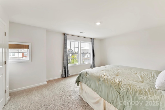 bedroom featuring visible vents, multiple windows, baseboards, and light colored carpet