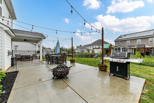 view of patio with an outdoor fire pit, a fenced backyard, a residential view, a grill, and a playground