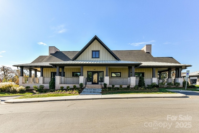 view of front of house featuring metal roof, covered porch, board and batten siding, a standing seam roof, and a chimney