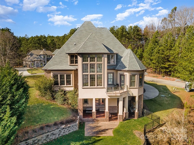 rear view of house featuring a yard, a patio, and a balcony