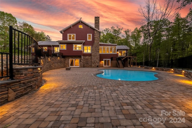 pool at dusk with a patio area