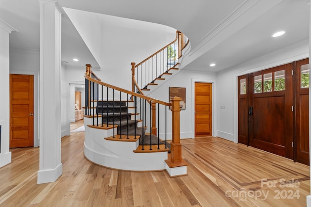 foyer entrance with crown molding and hardwood / wood-style floors