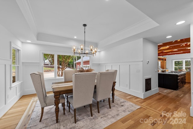 dining area with ornamental molding, a chandelier, and light hardwood / wood-style floors