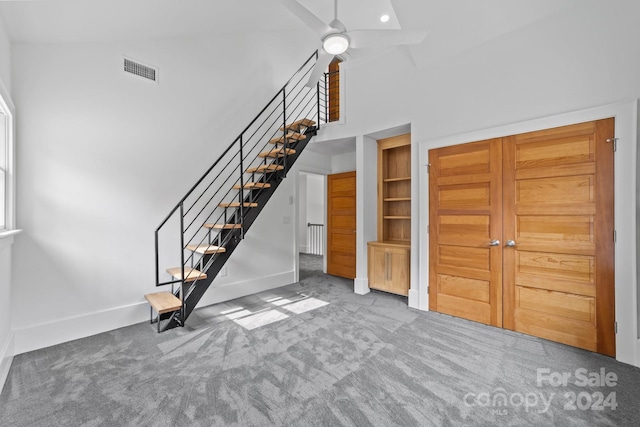 interior space featuring a high ceiling, carpet flooring, and ceiling fan