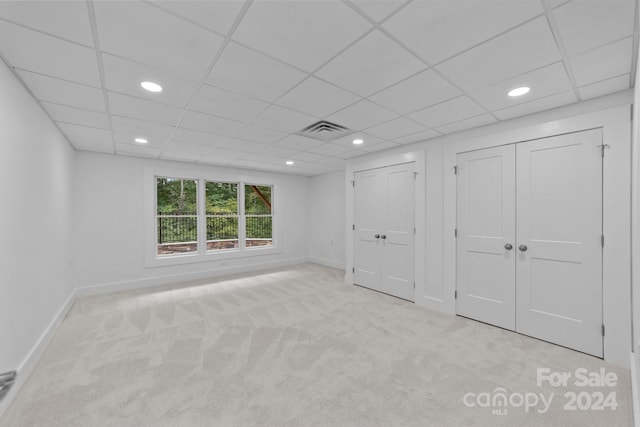 interior space featuring a paneled ceiling and light carpet