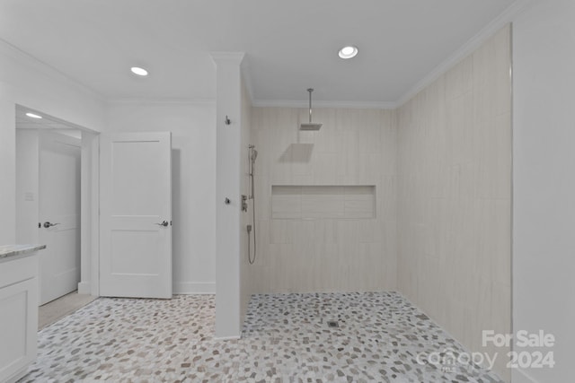 bathroom with ornamental molding, vanity, and tiled shower