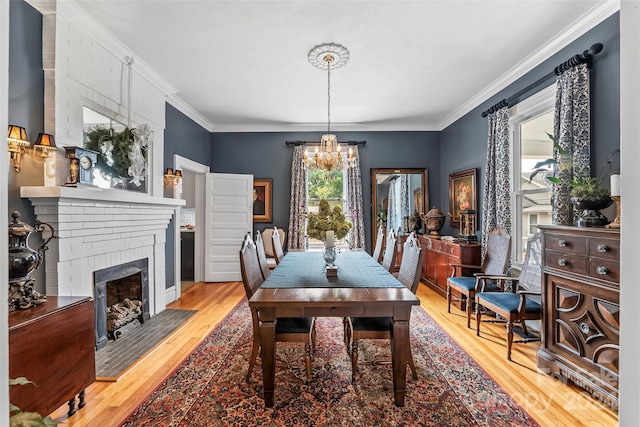 404 Avery Ave, Morganton, NC 28655 - dining area featuring light wood-style floors, a chandelier, a brick fireplace, and crown molding