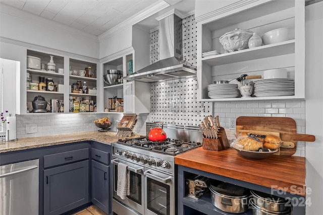 kitchen with wall chimney exhaust hood, tasteful backsplash, light stone counters, and range with two ovens