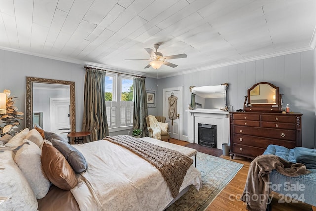 bedroom with ceiling fan, hardwood / wood-style flooring, a fireplace, and ornamental molding