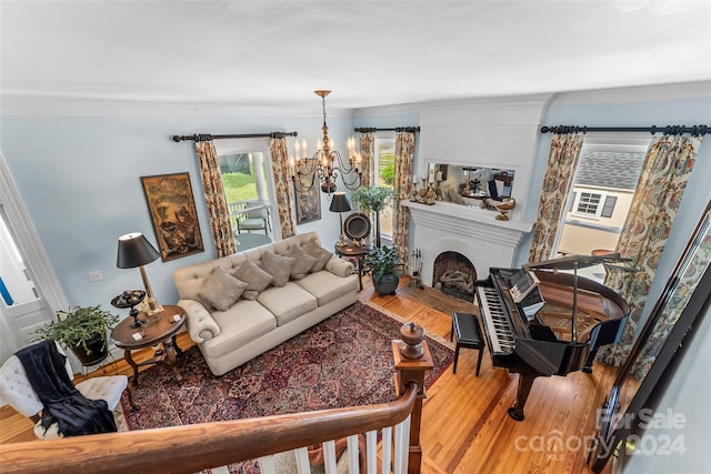 living room featuring a notable chandelier, wood-type flooring, and ornamental molding