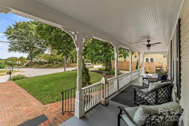 wooden deck featuring ceiling fan, outdoor lounge area, a porch, and a lawn