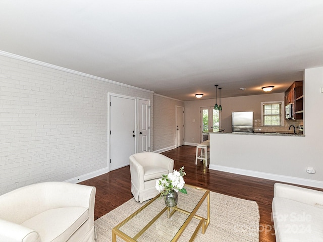 living room with ornamental molding, brick wall, sink, and dark hardwood / wood-style flooring