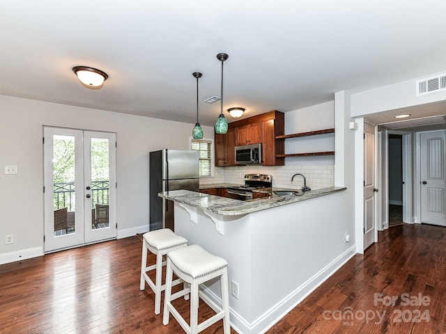 kitchen featuring appliances with stainless steel finishes, kitchen peninsula, dark hardwood / wood-style flooring, and light stone counters