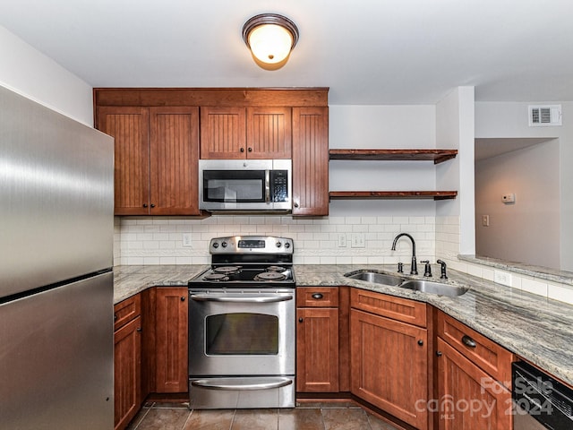 kitchen featuring backsplash, light stone countertops, stainless steel appliances, dark tile patterned floors, and sink