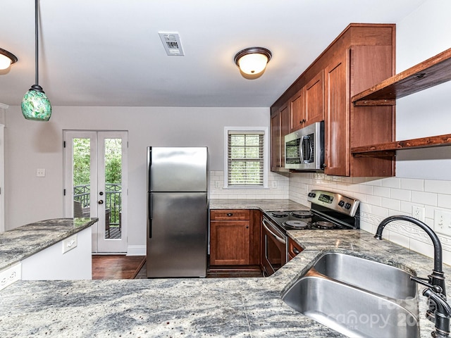 kitchen with sink, hanging light fixtures, decorative backsplash, stainless steel appliances, and dark stone countertops