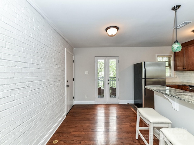 kitchen featuring stainless steel fridge, light stone counters, french doors, decorative light fixtures, and dark hardwood / wood-style floors