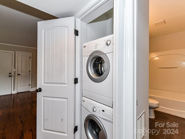 washroom featuring stacked washer / dryer, crown molding, and dark hardwood / wood-style floors