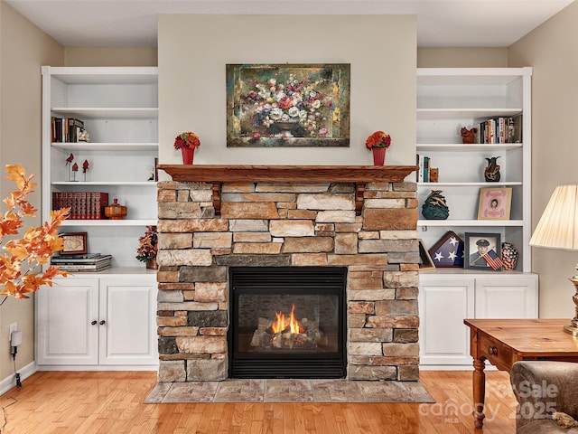 room details featuring built in shelves, a stone fireplace, and wood-type flooring