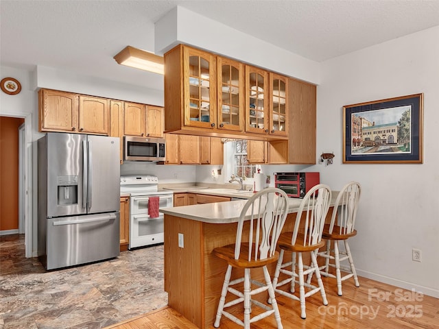 kitchen with kitchen peninsula, a kitchen breakfast bar, a textured ceiling, stainless steel appliances, and sink