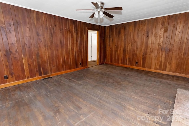 unfurnished room with ceiling fan, dark wood-type flooring, wooden walls, and ornamental molding