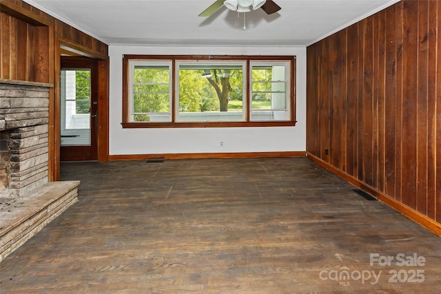 unfurnished living room with ornamental molding, a fireplace, and wood walls