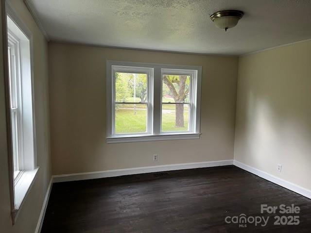 empty room with a textured ceiling and dark hardwood / wood-style floors