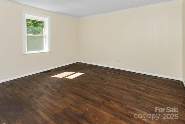 spare room with dark hardwood / wood-style flooring and crown molding