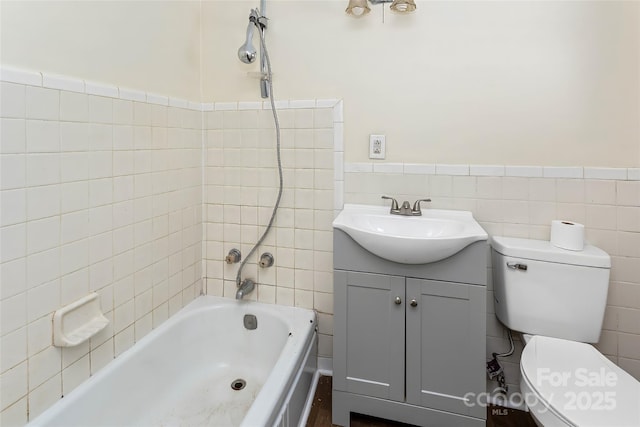 full bathroom featuring toilet, tile walls, tiled shower / bath, and vanity