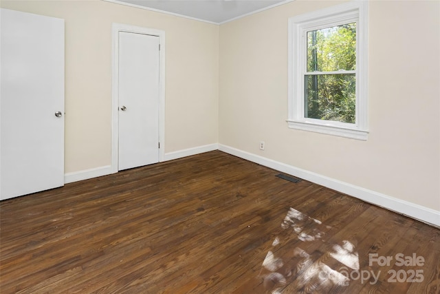 empty room with dark wood-type flooring and crown molding