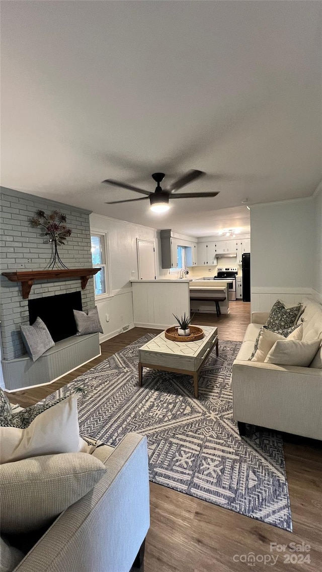 living room featuring dark hardwood / wood-style floors, ceiling fan, sink, and a brick fireplace