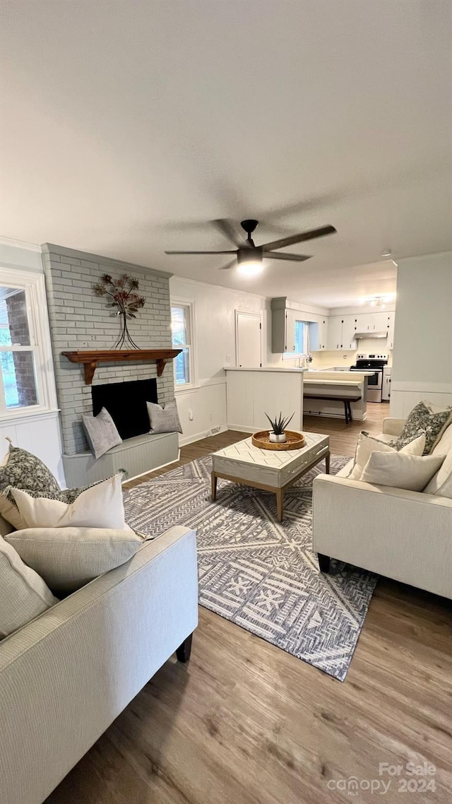 living room featuring a brick fireplace, hardwood / wood-style flooring, and ceiling fan