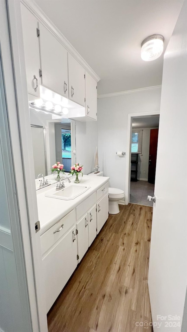 bathroom with vanity, hardwood / wood-style flooring, walk in shower, crown molding, and toilet