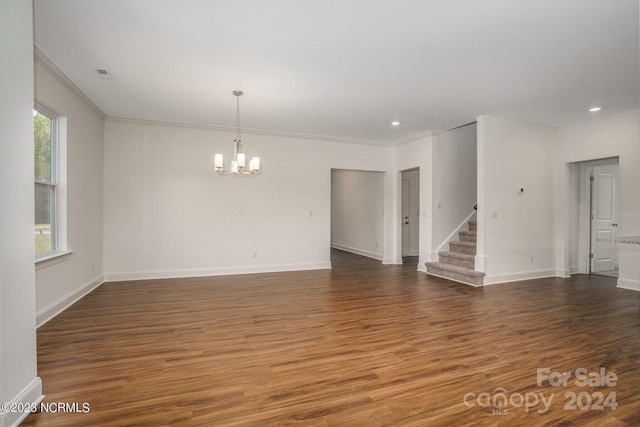 spare room with an inviting chandelier, crown molding, and dark hardwood / wood-style flooring