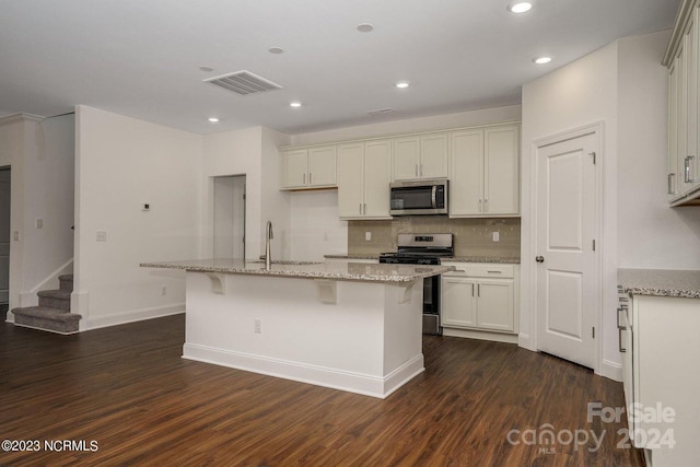 kitchen featuring a center island with sink, stainless steel appliances, and dark wood-type flooring