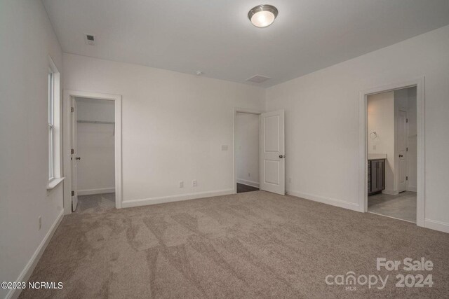 unfurnished bedroom featuring light carpet, a closet, and connected bathroom