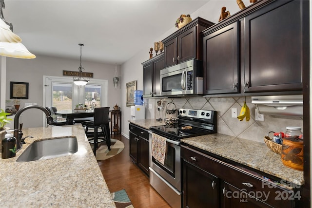 kitchen featuring dark brown cabinets, dark hardwood / wood-style floors, sink, stainless steel appliances, and decorative light fixtures