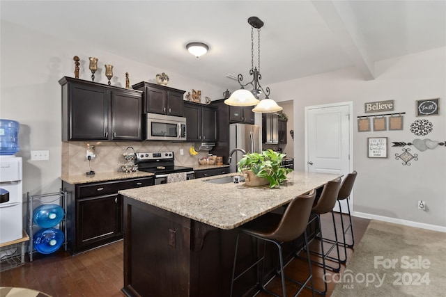 kitchen with pendant lighting, dark hardwood / wood-style floors, a kitchen island with sink, a kitchen breakfast bar, and stainless steel appliances