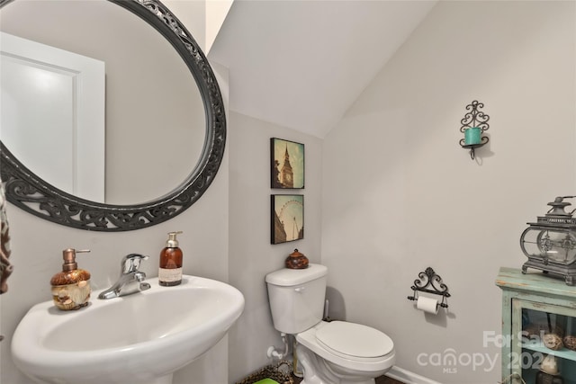 bathroom with vaulted ceiling, sink, and toilet