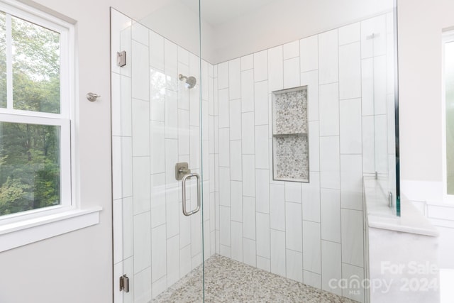 bathroom with a shower with shower door and a healthy amount of sunlight