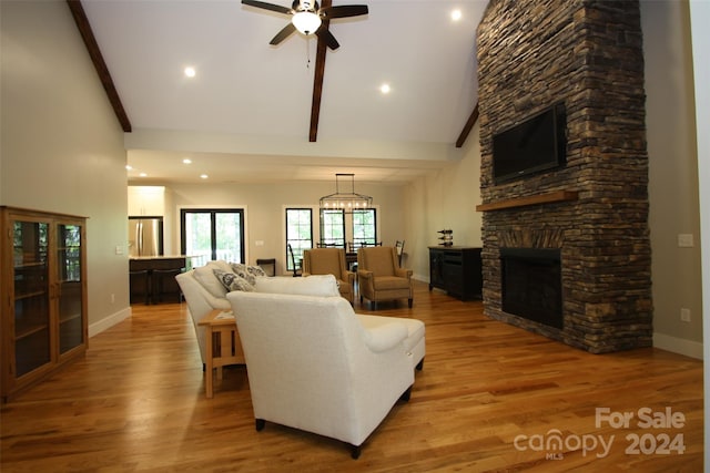 living room featuring ceiling fan with notable chandelier, beam ceiling, light hardwood / wood-style flooring, a fireplace, and high vaulted ceiling