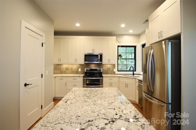 kitchen with light stone counters, sink, white cabinetry, appliances with stainless steel finishes, and dark hardwood / wood-style floors