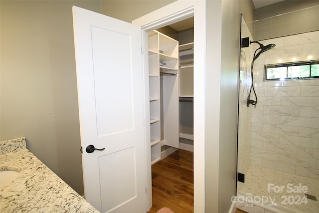 bathroom with walk in shower, vanity, and hardwood / wood-style floors