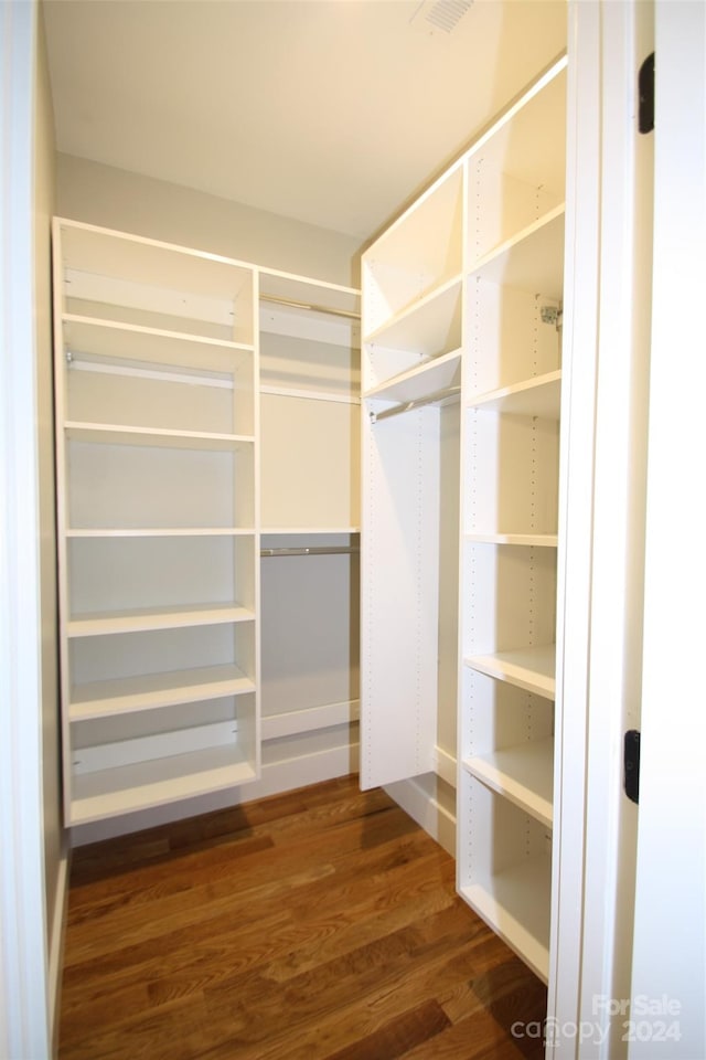 walk in closet with dark hardwood / wood-style floors