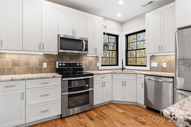 kitchen featuring white cabinets, visible vents, stainless steel appliances, and a sink