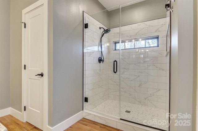 full bath with a stall shower, baseboards, and wood finished floors